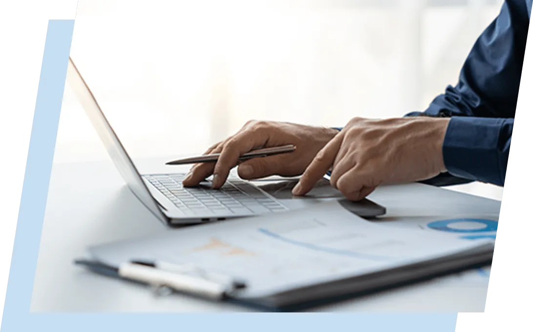 デスクでノートパソコンと書類を広げて作業している手元の写真