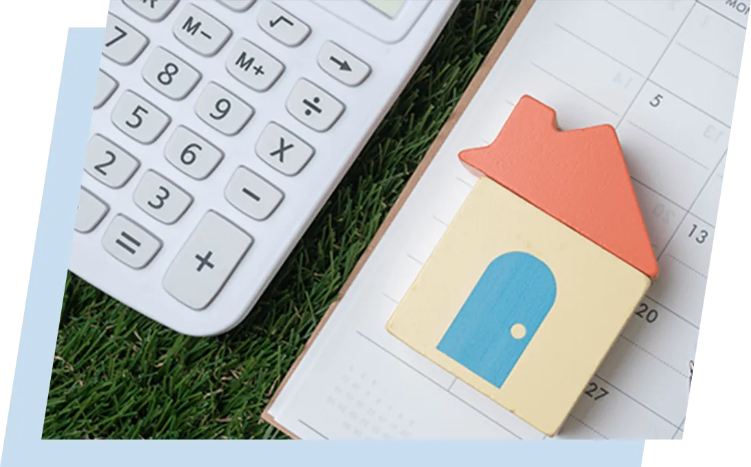 机上に置かれた電卓と家の形をした小物